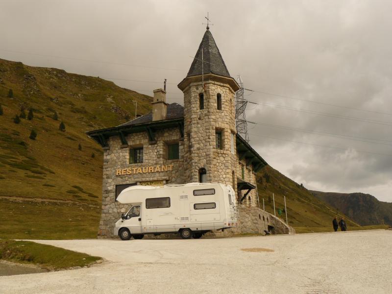 De camper van Hans en Anita bij een oude kerktoren in een berglandschap